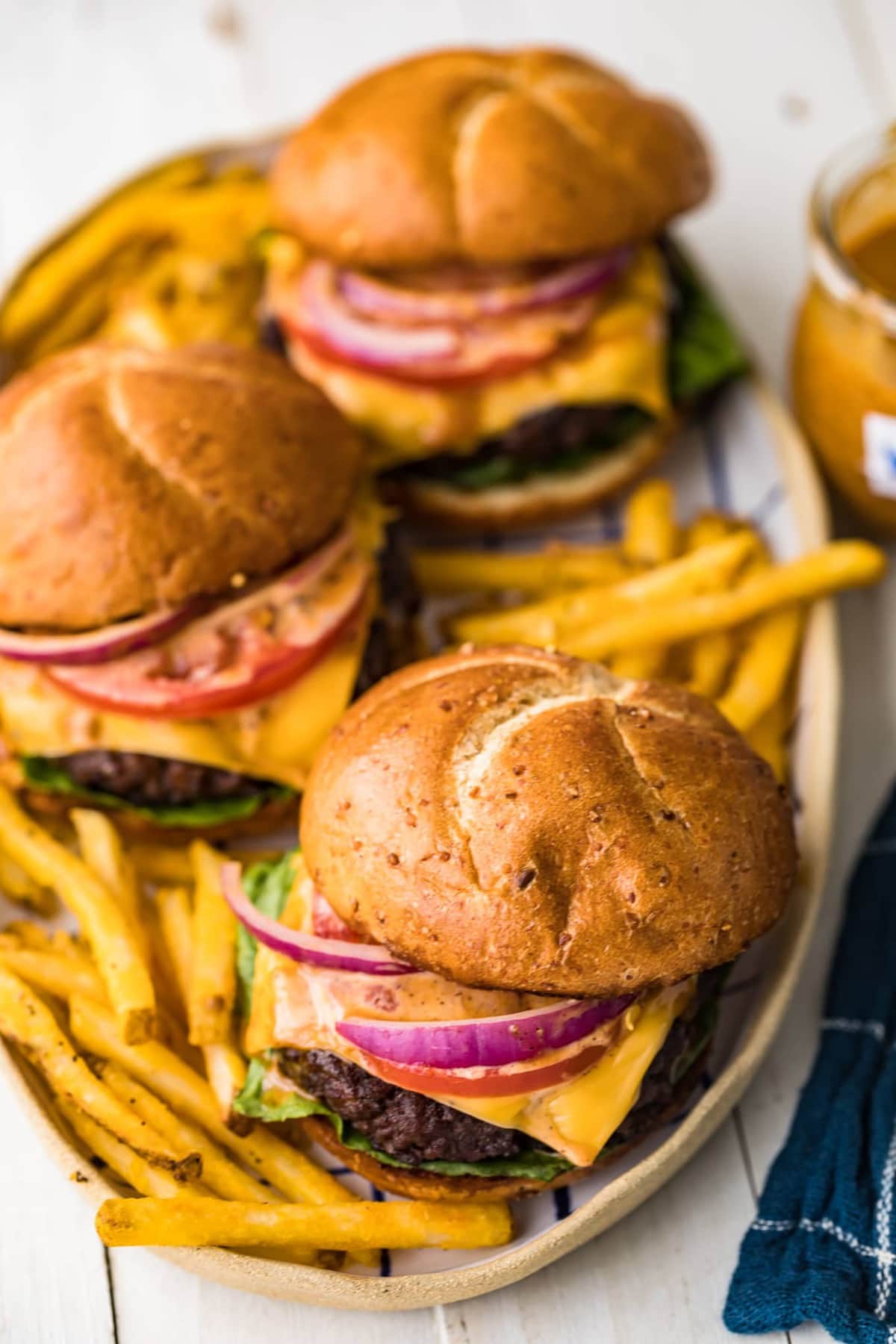 Three juicy grilled burgers served with fries