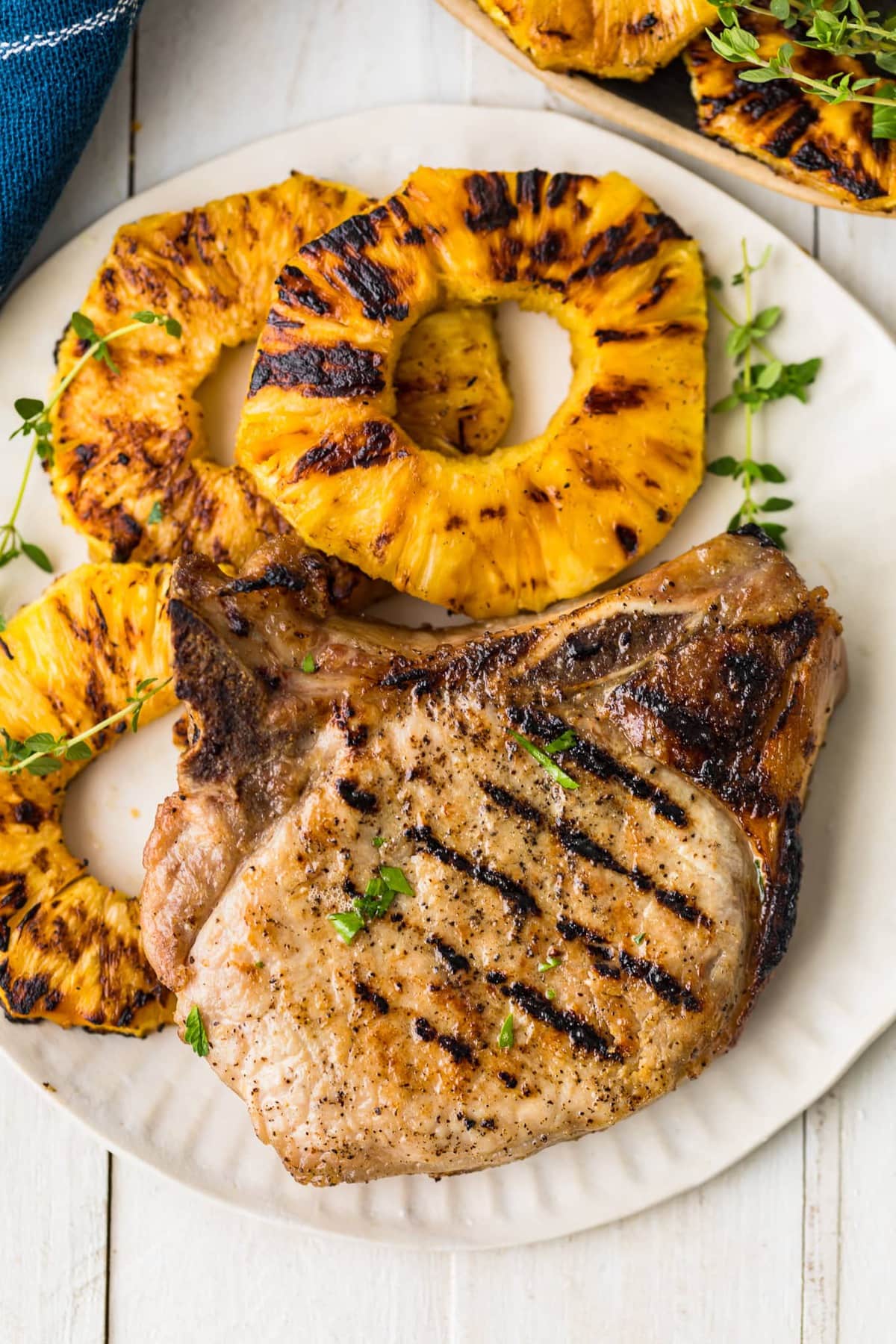 A grilled pork chop served with three pineapple rings