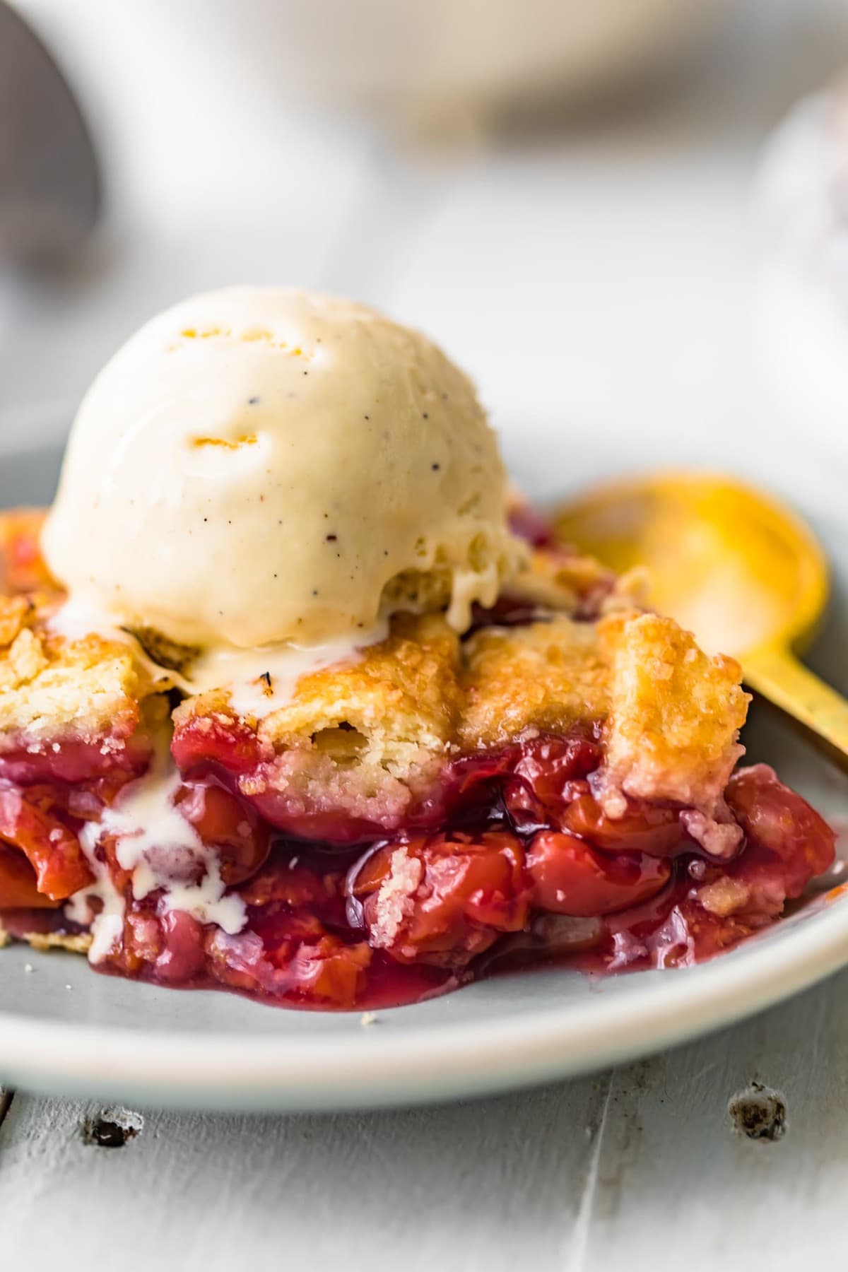 A slice of homemade cherry pie with ice cream on top