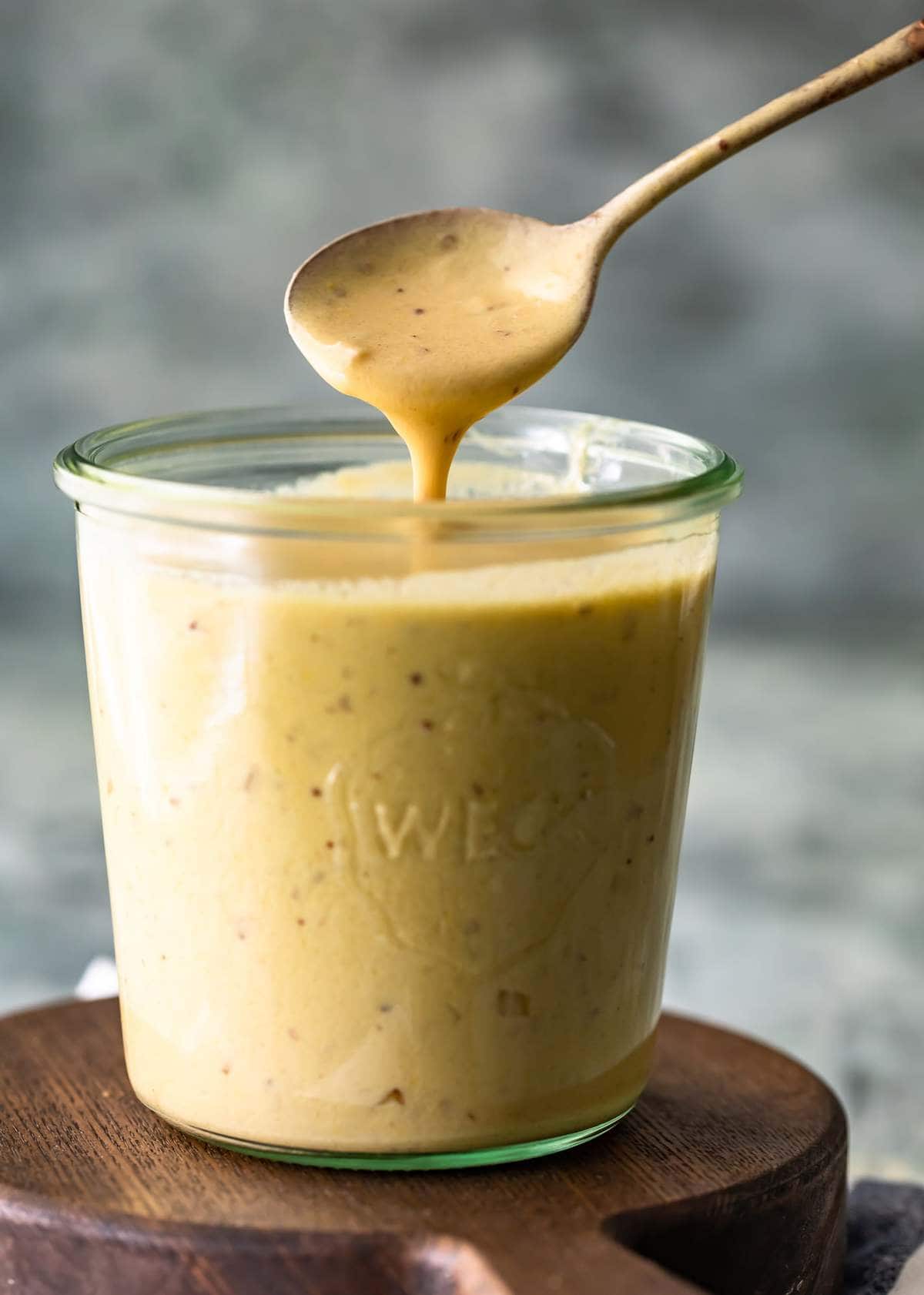 Close up of mustard cream sauce dripping from a spoon