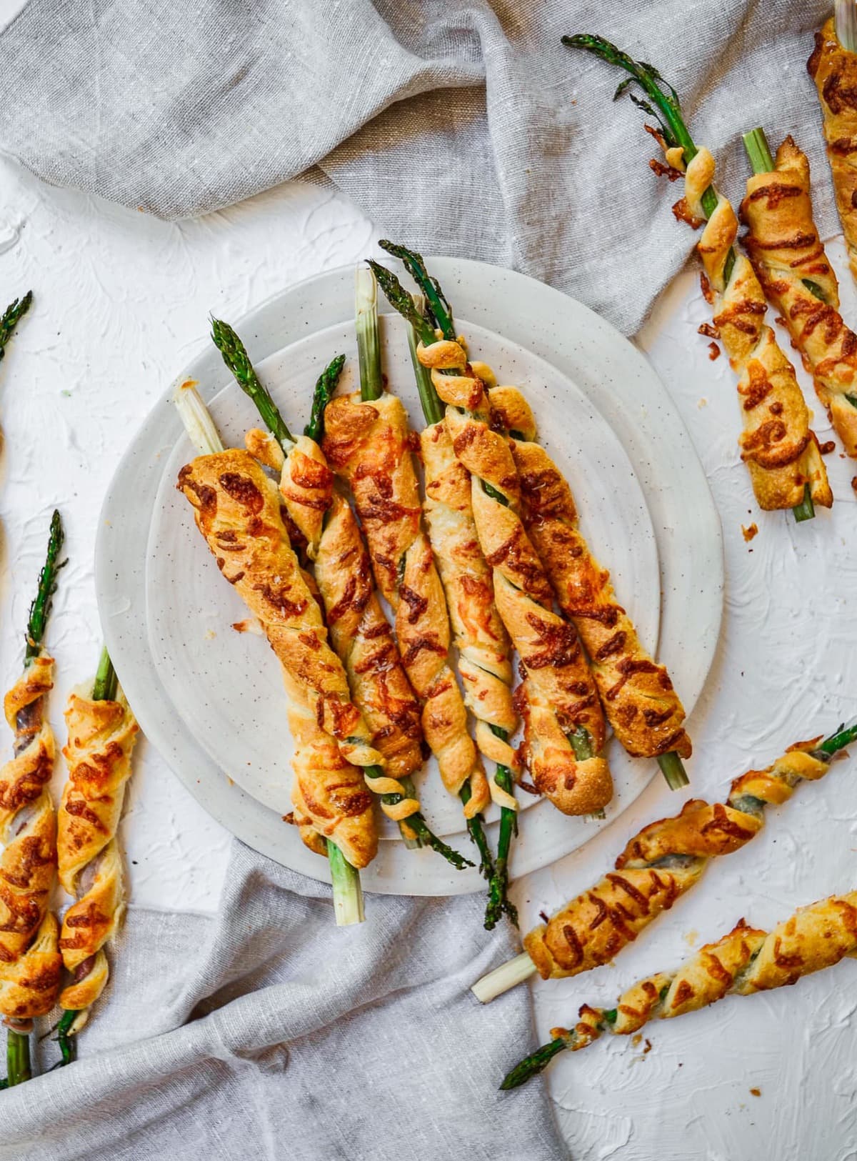 Asparagus plus crescent rolls equals the best crescent roll appetizers for any meal or party! These cheesy asparagus puff pastry spirals are so cute, so tasty, and so easy to make. They definitely make eating your vegetables a whole lot more fun for the kids (and us adults)! A plate of Cheesy Asparagus Crescent Roll appetizers. Recipe via Thecookierookie.com