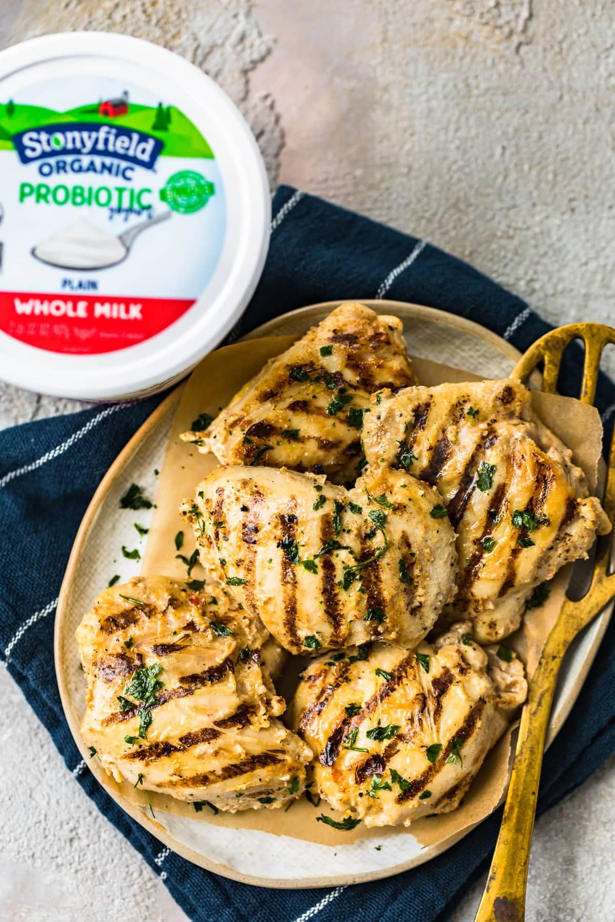 a plate of chicken thighs next to a container of yogurt