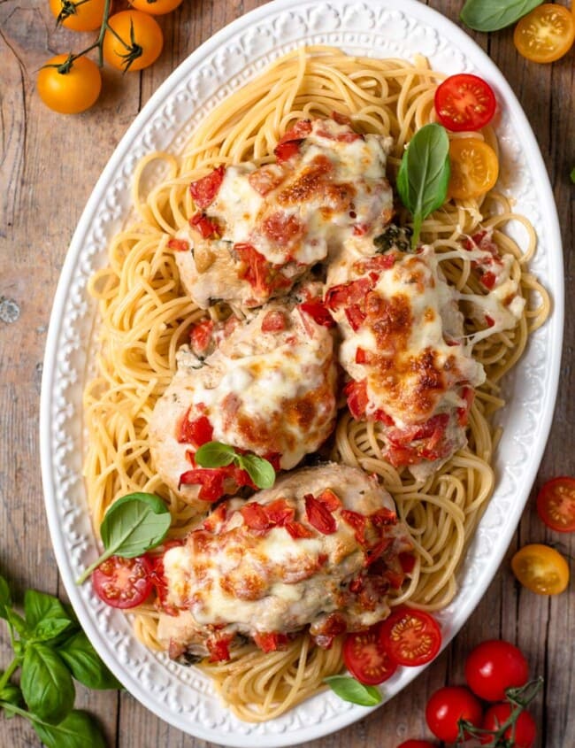 overhead shot of bruschetta chicken on top of pasta on plate