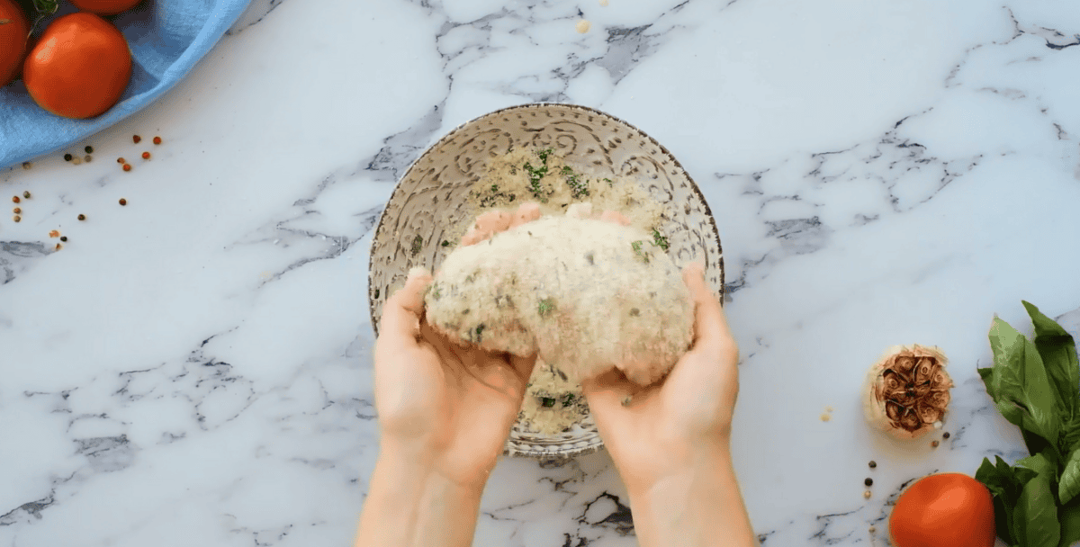 Coating chicken in the Parmesan and basil mixture. 
