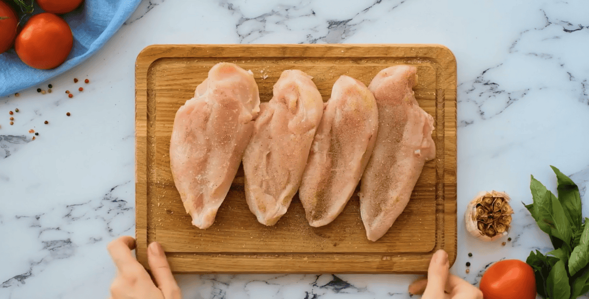 Seasoned chicken on a wooden cutting board.