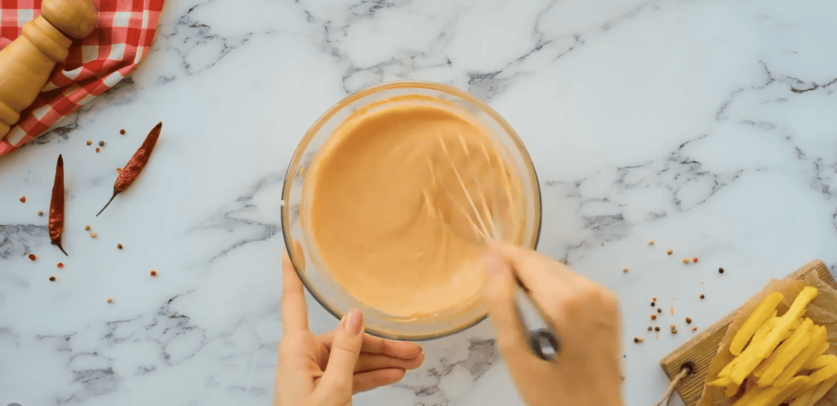 Fry sauce in a glass bowl being mixed with a whisk. 