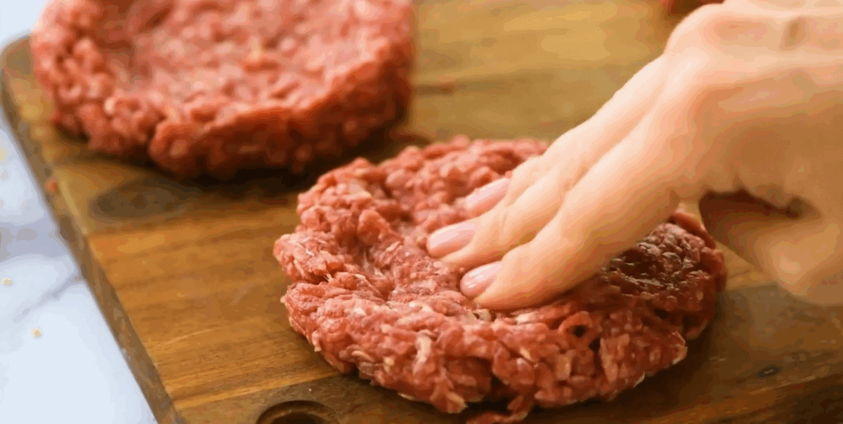 Pressing the burgers so they are flat. 