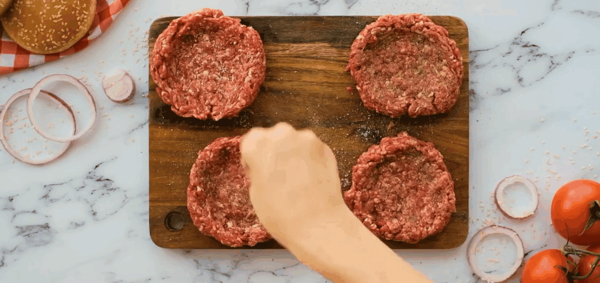 Seasoning the burger patties.