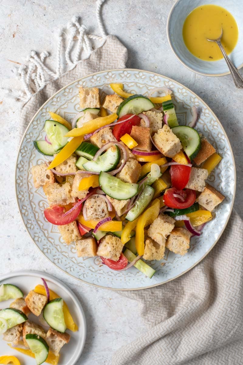 An overhead shot of a panzanella salad on a plate with vinaigrette