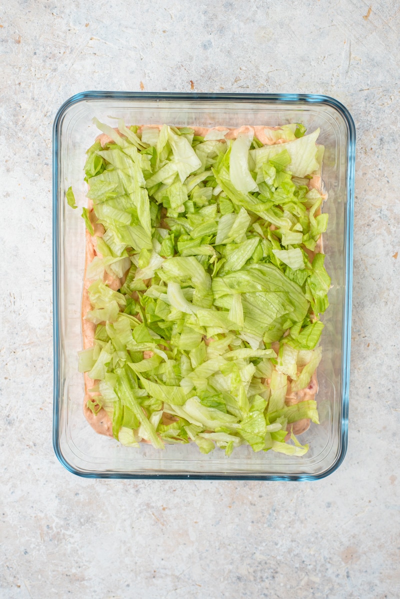 An overhead shot of lettuce on a layered taco dip