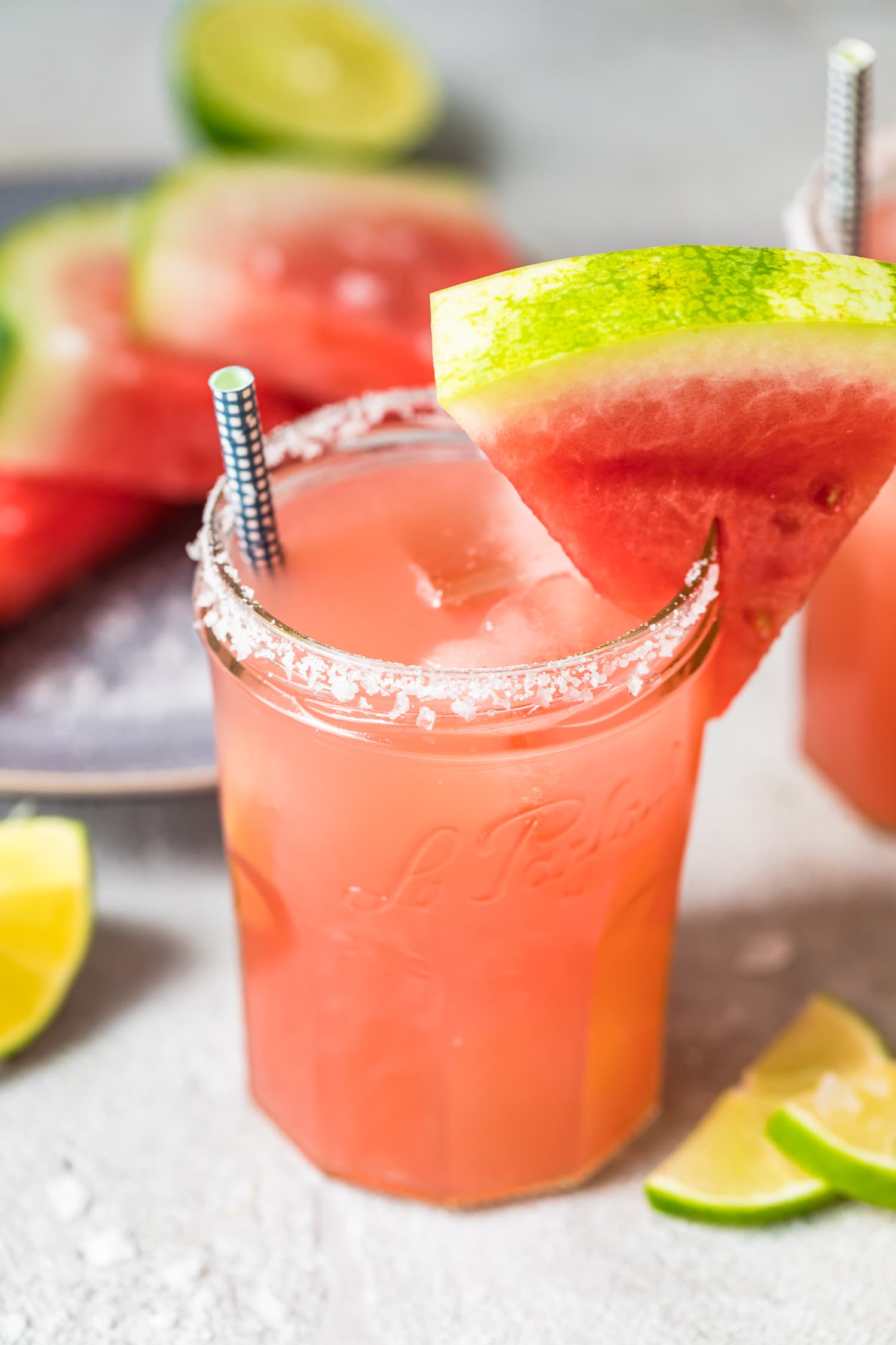 watermelon margarita in a jar glass with a salted rim, and a watermelon wedge as garnish