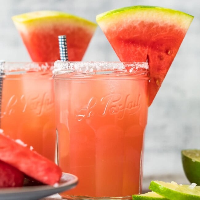 two watermelon margaritas with sliced watermelons on top of the glasses