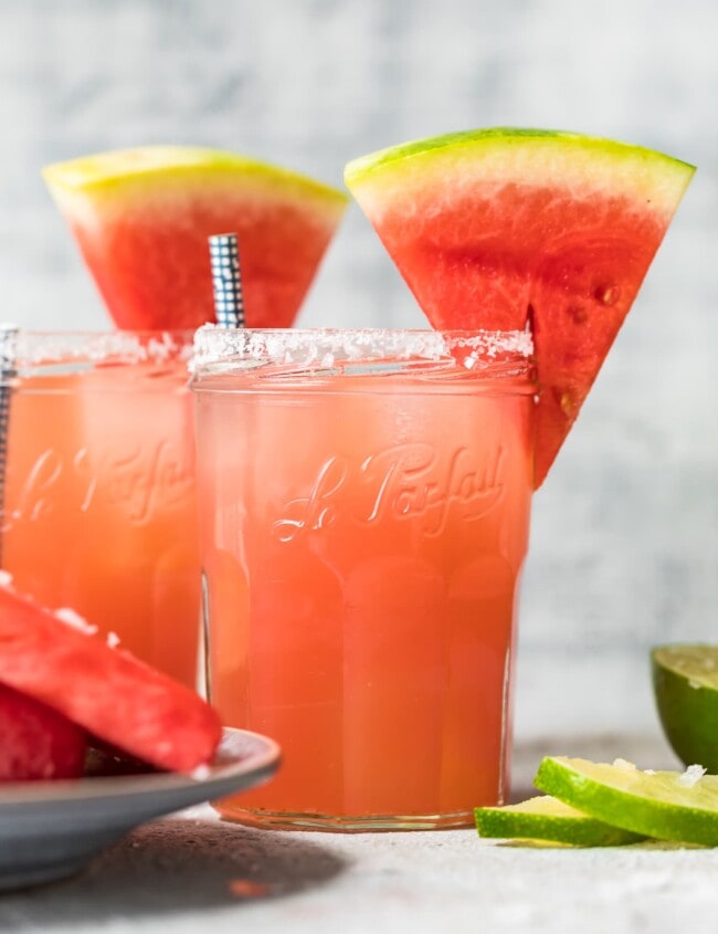 two watermelon margaritas with sliced watermelons on top of the glasses