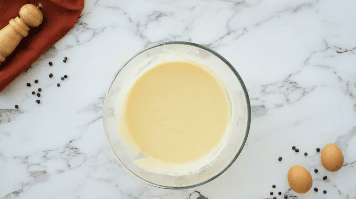 A bowl with eggs, flour, and butter on a marble countertop preparing delicious Chocolate Chip Pancakes.