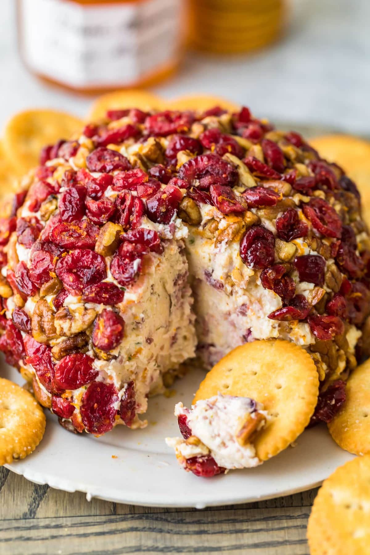 A christmas cheese ball with cranberries an orange on a serving plate