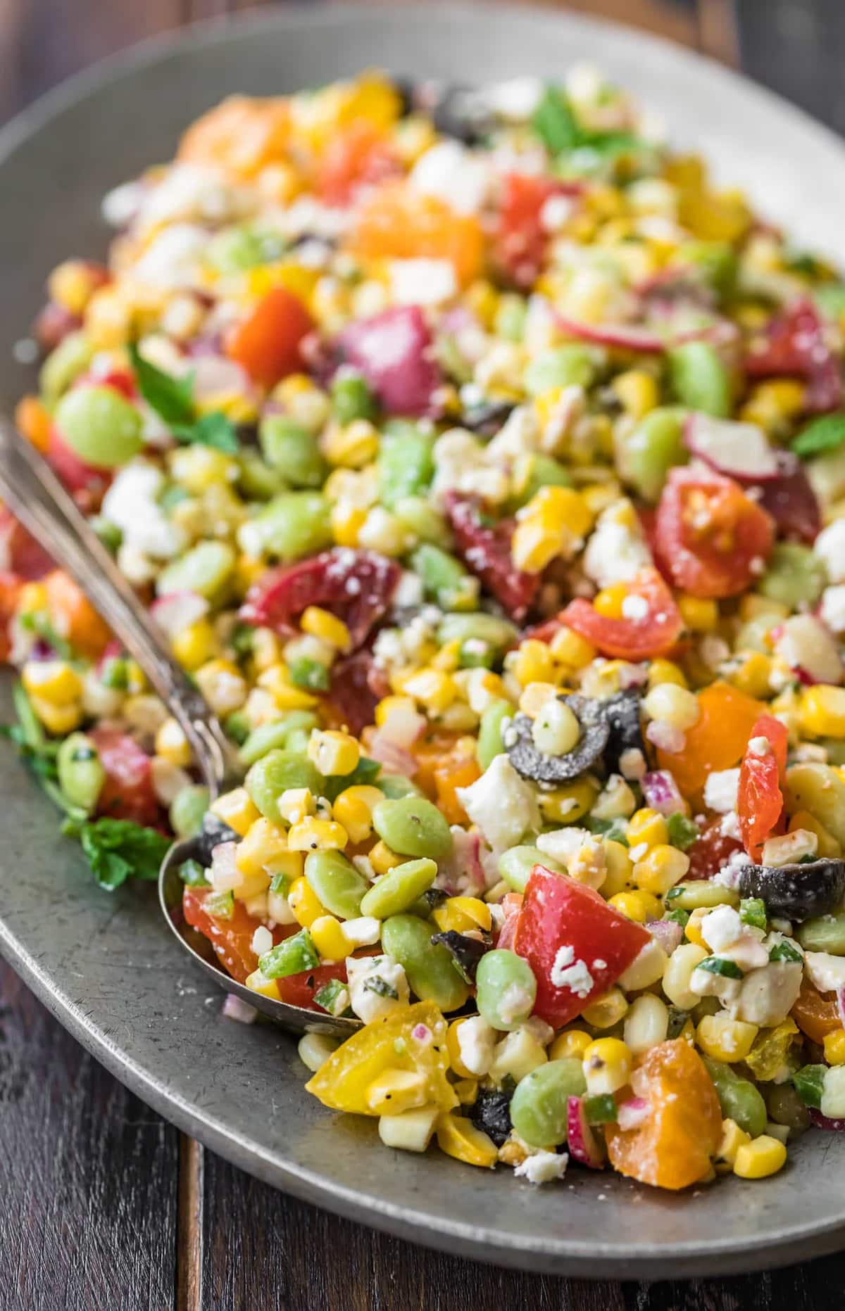 A spoon lifting some salad off of a plate