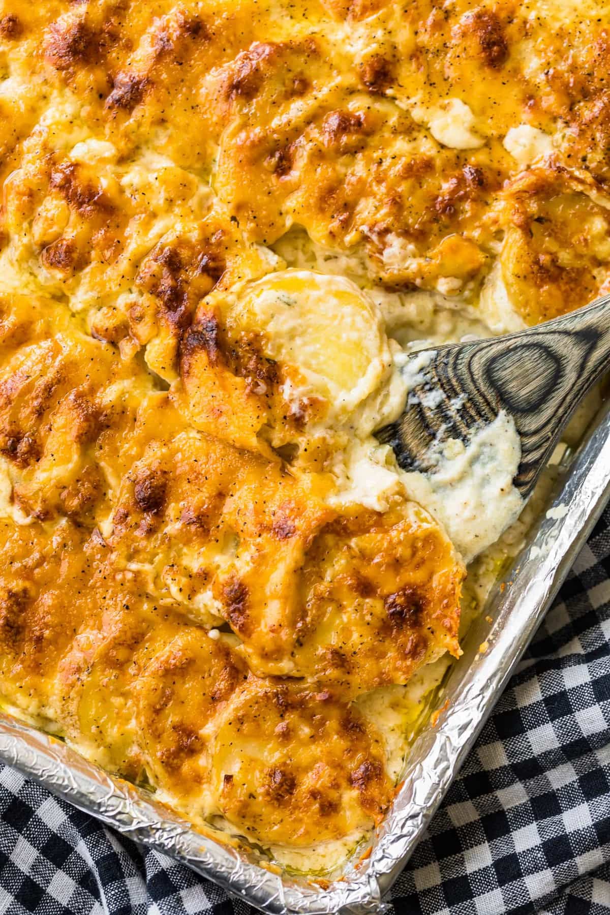 Cheesy scalloped potato casserole in a baking dish with a fork.