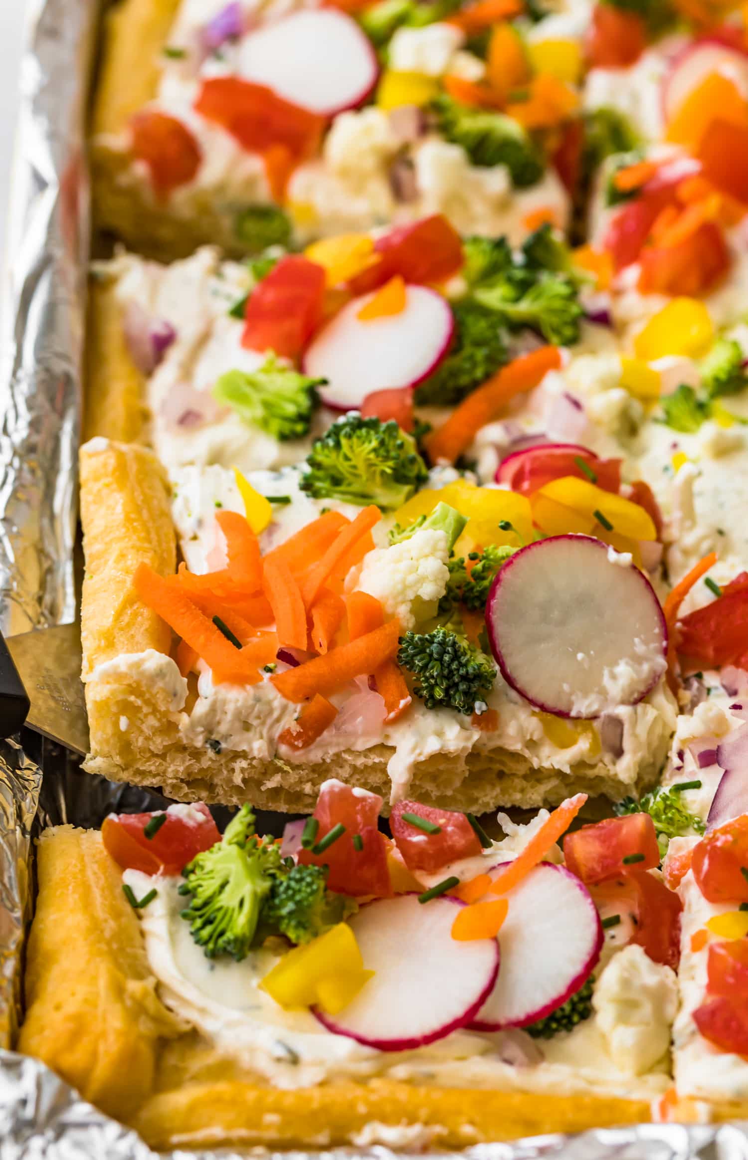 A square of veggie pizza being lifted up