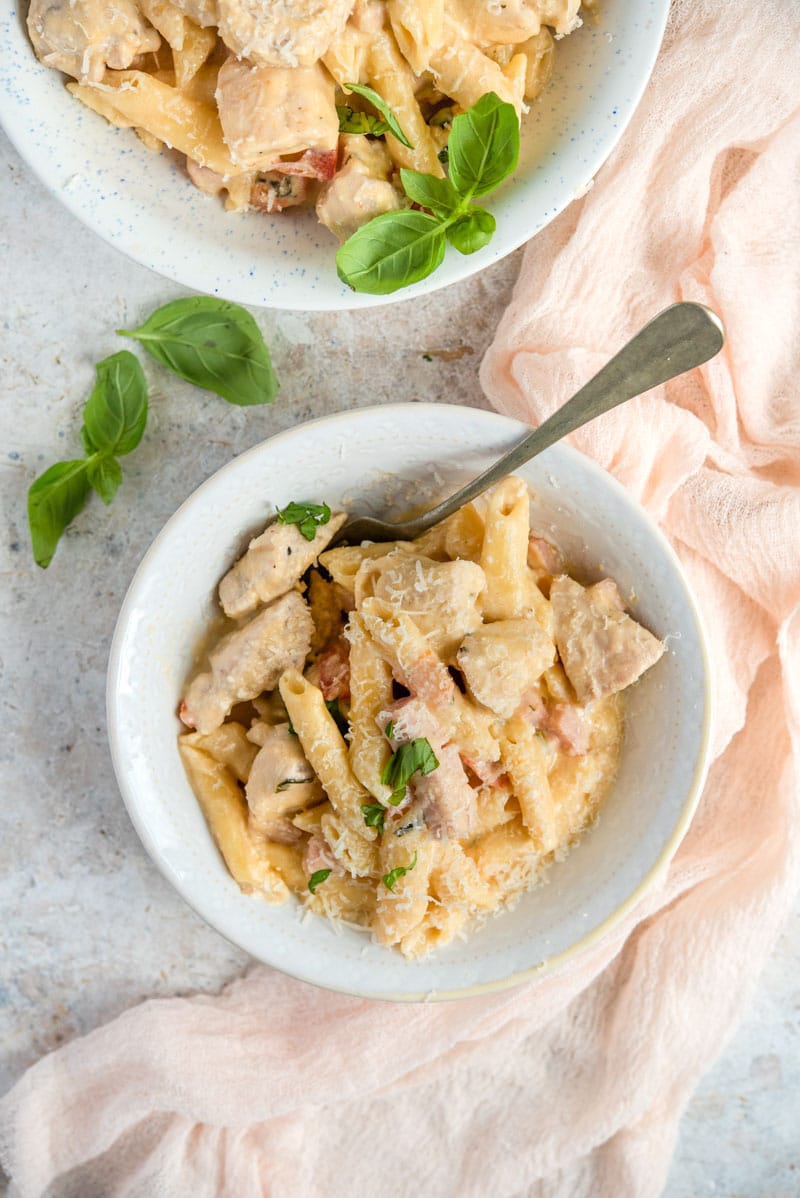 An overhead shot of one pot chicken alfredo in two bowls with basil