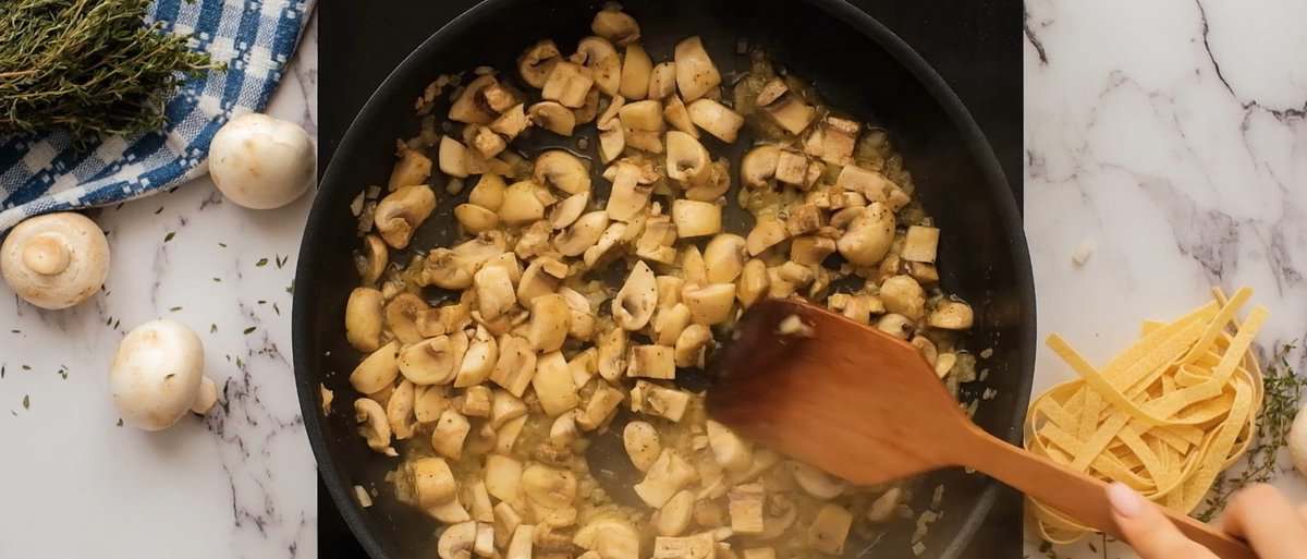 Sauteeing mushrooms in a skillet with onions.