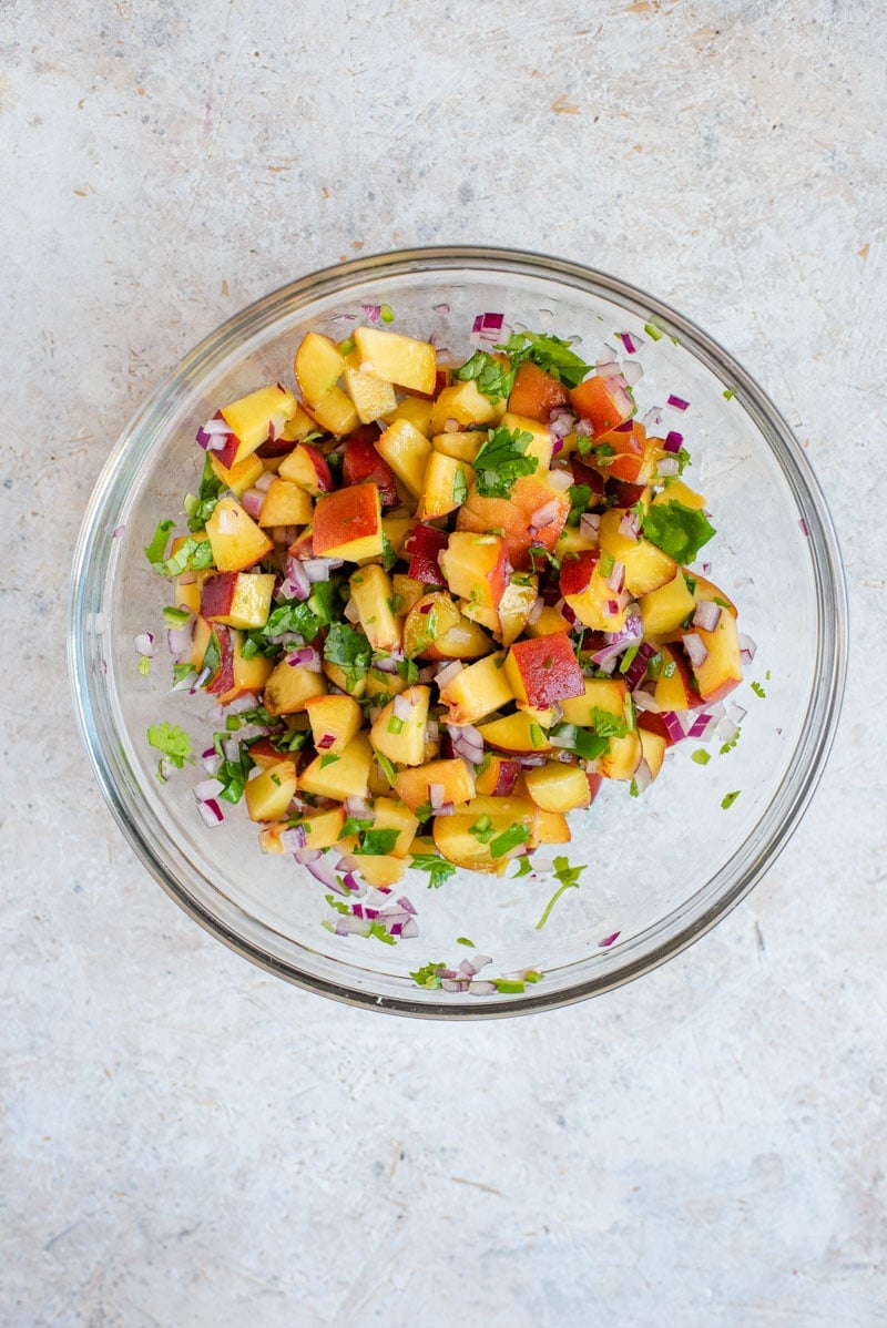 An overhead shot of peach salsa in a bowl for serving with grilled salmon fillet