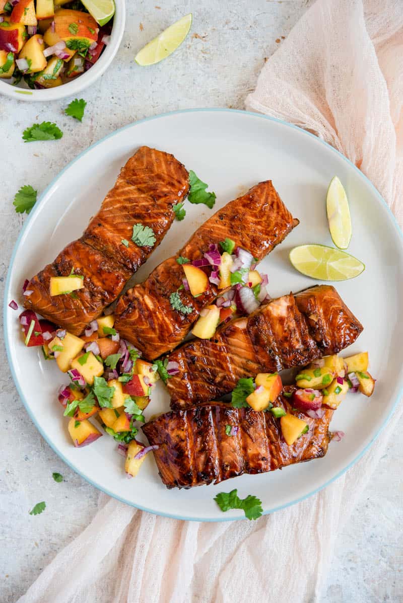 An overhead shot grilled salmon fillets on a plate with peach salsa