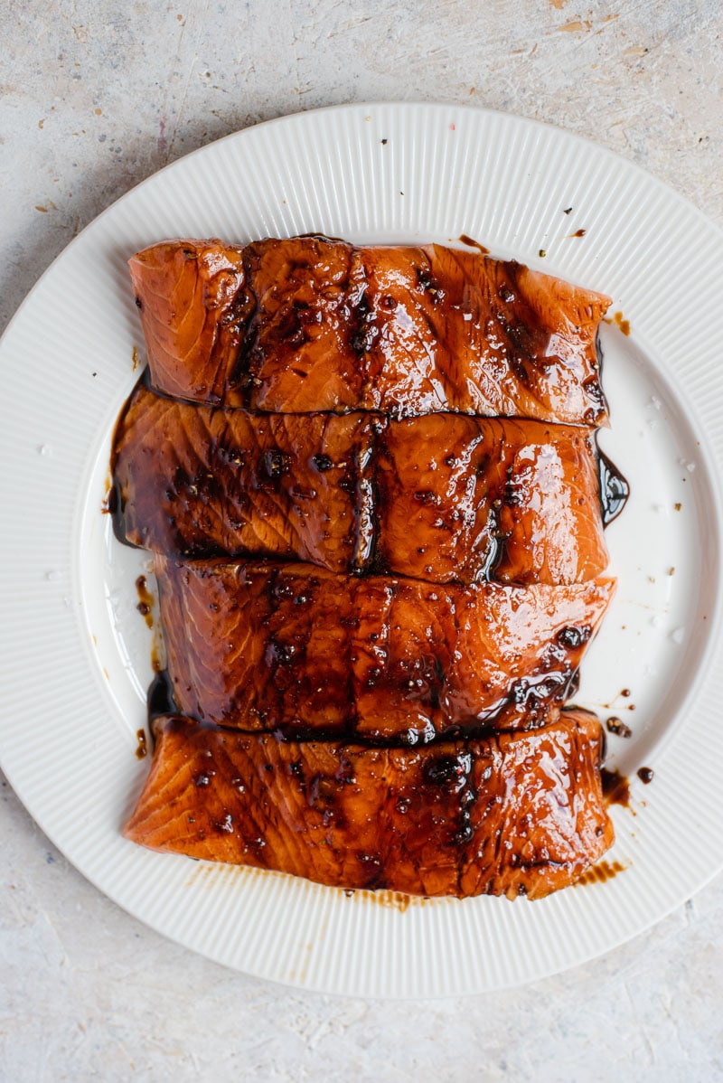 An overhead shot of salmon fillets brushed with a marinade on a plate