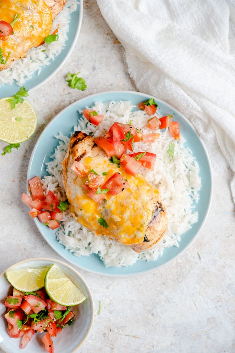 Tequila Lime Chicken on a plate with cheese, rice and salsa.