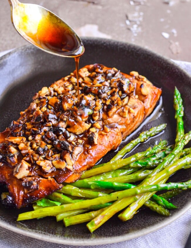 salmon and asparagus in skillet with glaze being spooned on it
