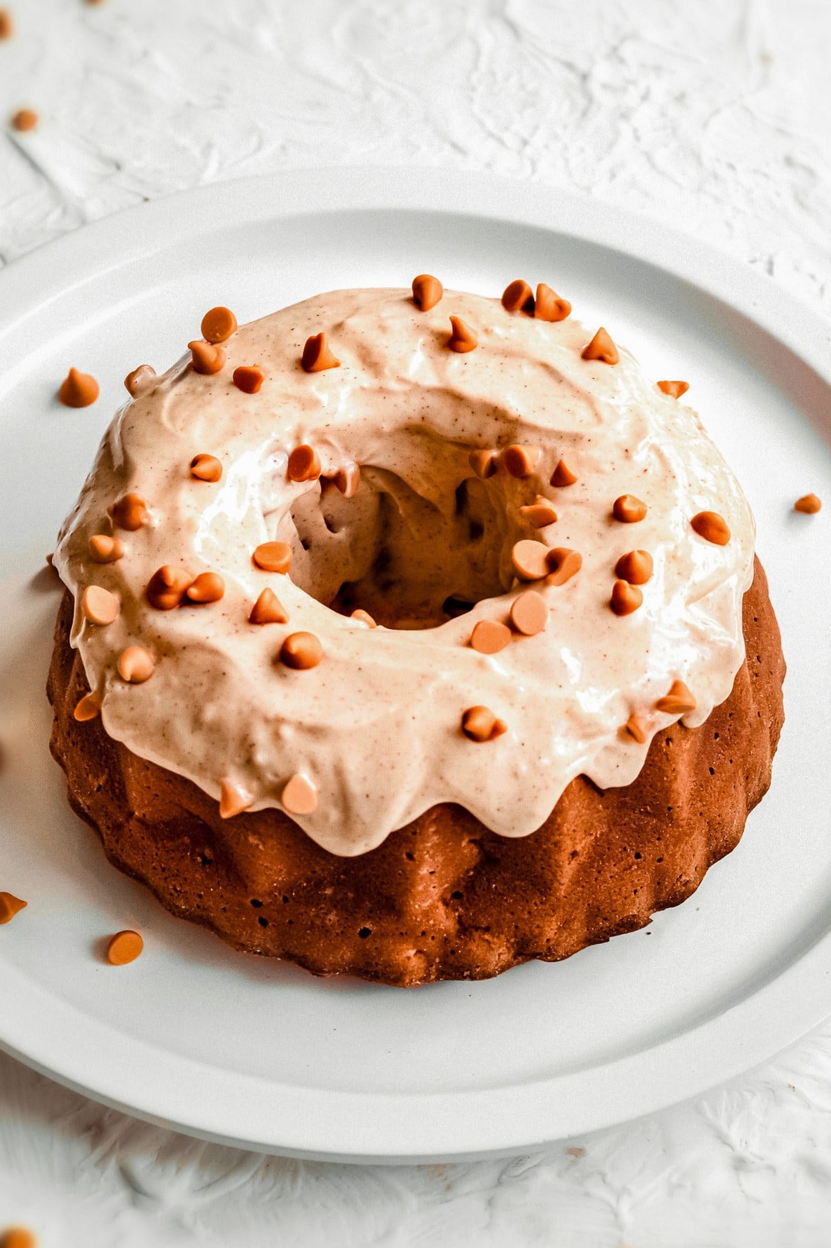 Chunky Apple Bundt Cake topped with cream cheese icing and cinnamon chips.