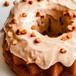 chunky apple bundpt cake covered in frosting on a white plate