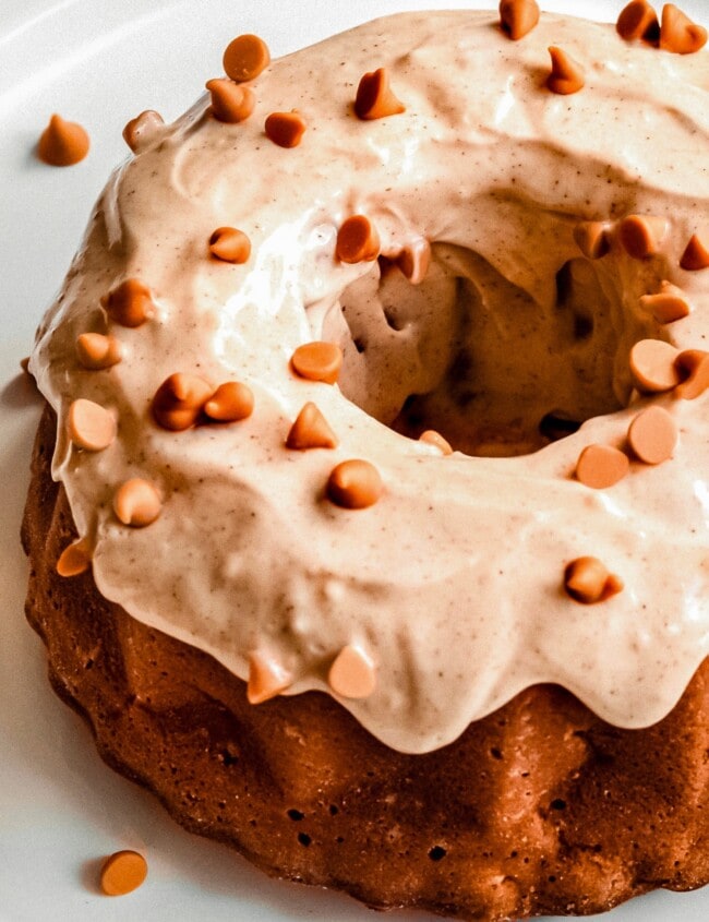 chunky apple bundpt cake covered in frosting on a white plate