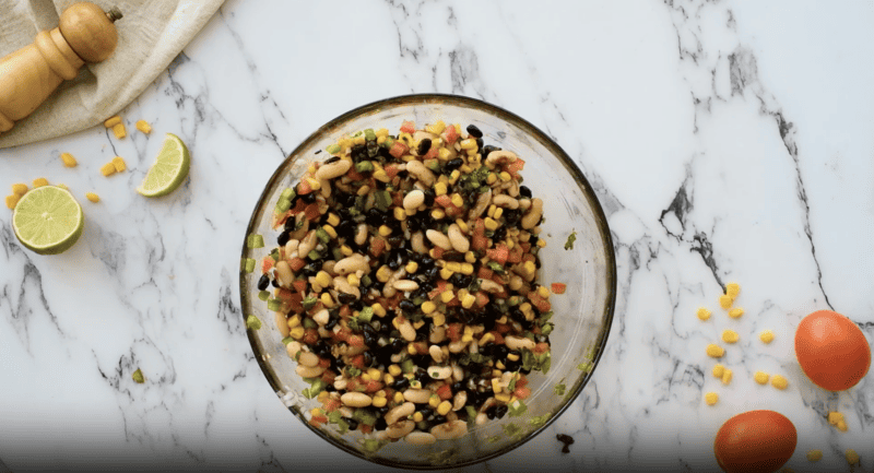 A bowl of Texas caviar, also known as cowboy caviar, on a marble table.