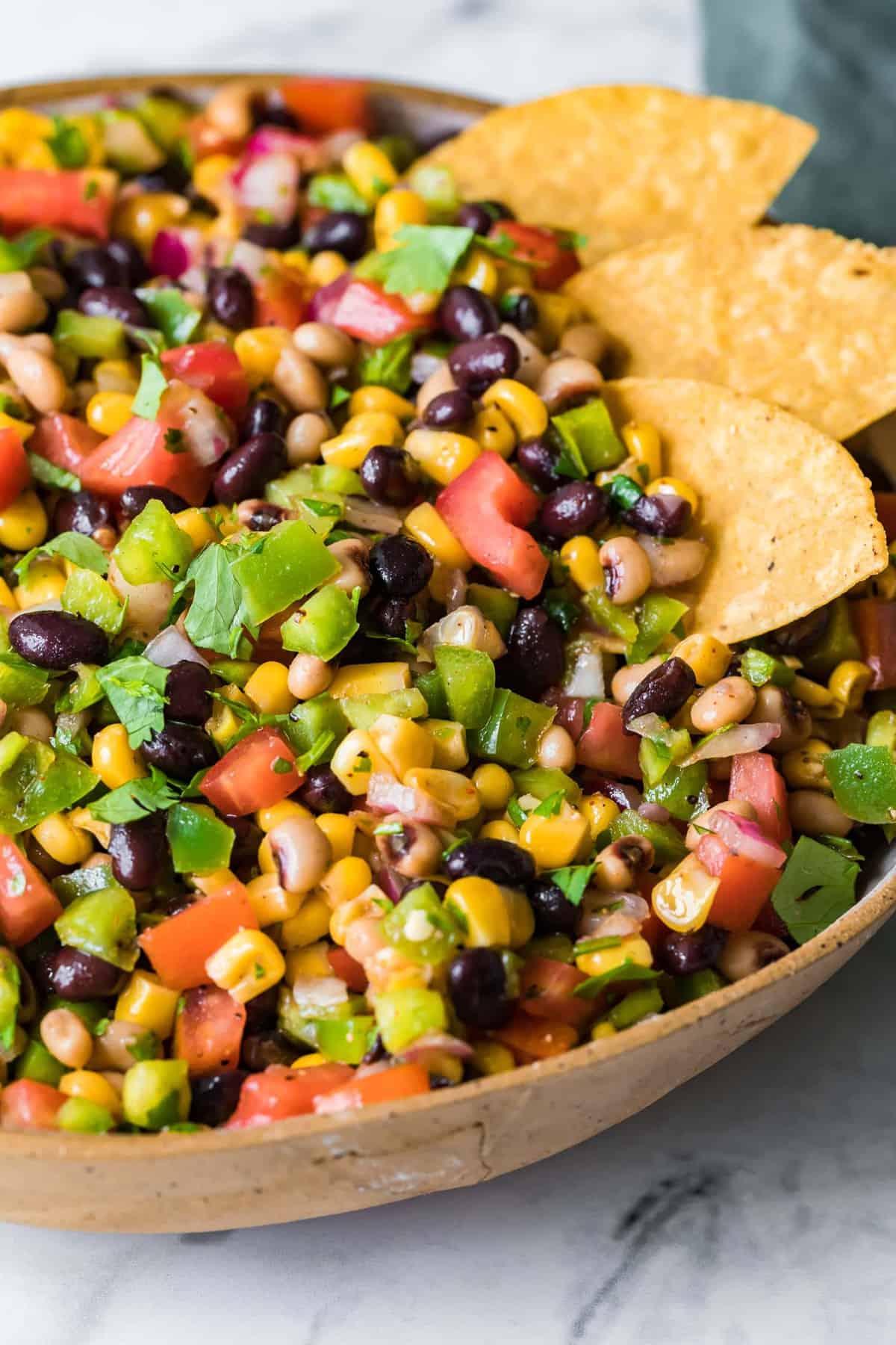 Cowboy caviar in a serving bowl on a marble work surface