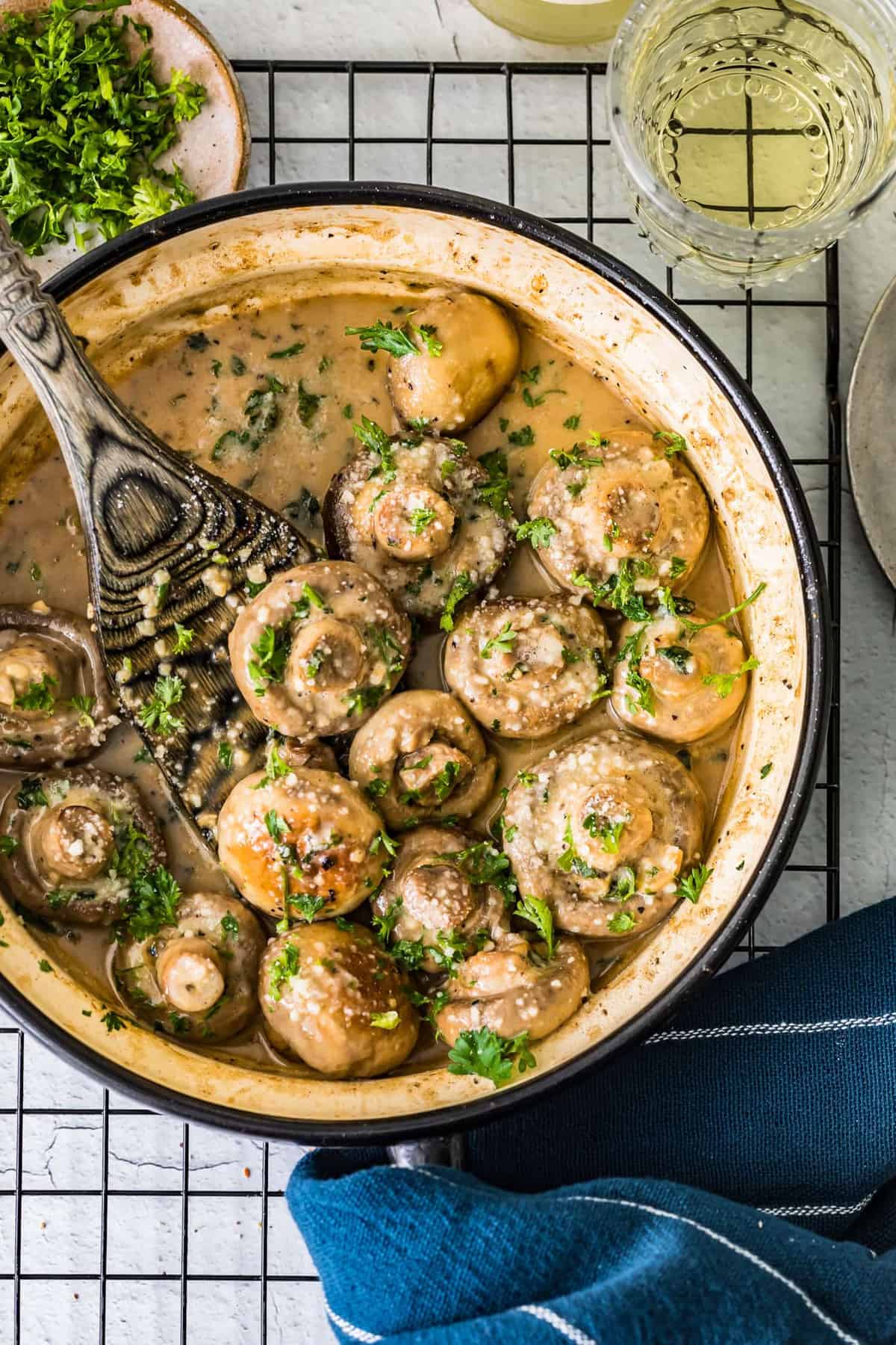 Top shot of creamy garlic mushrooms in a pan with a wooden spoon