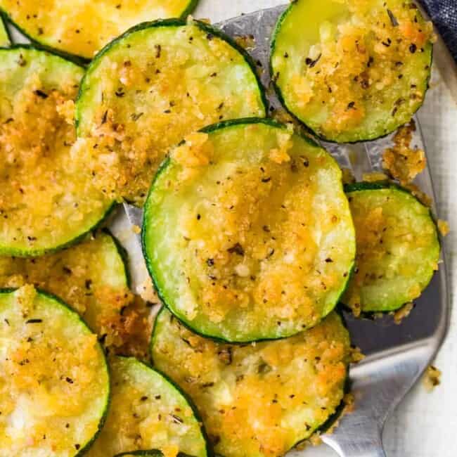 Crispy baked zucchini slices arranged on a plate with a fork.