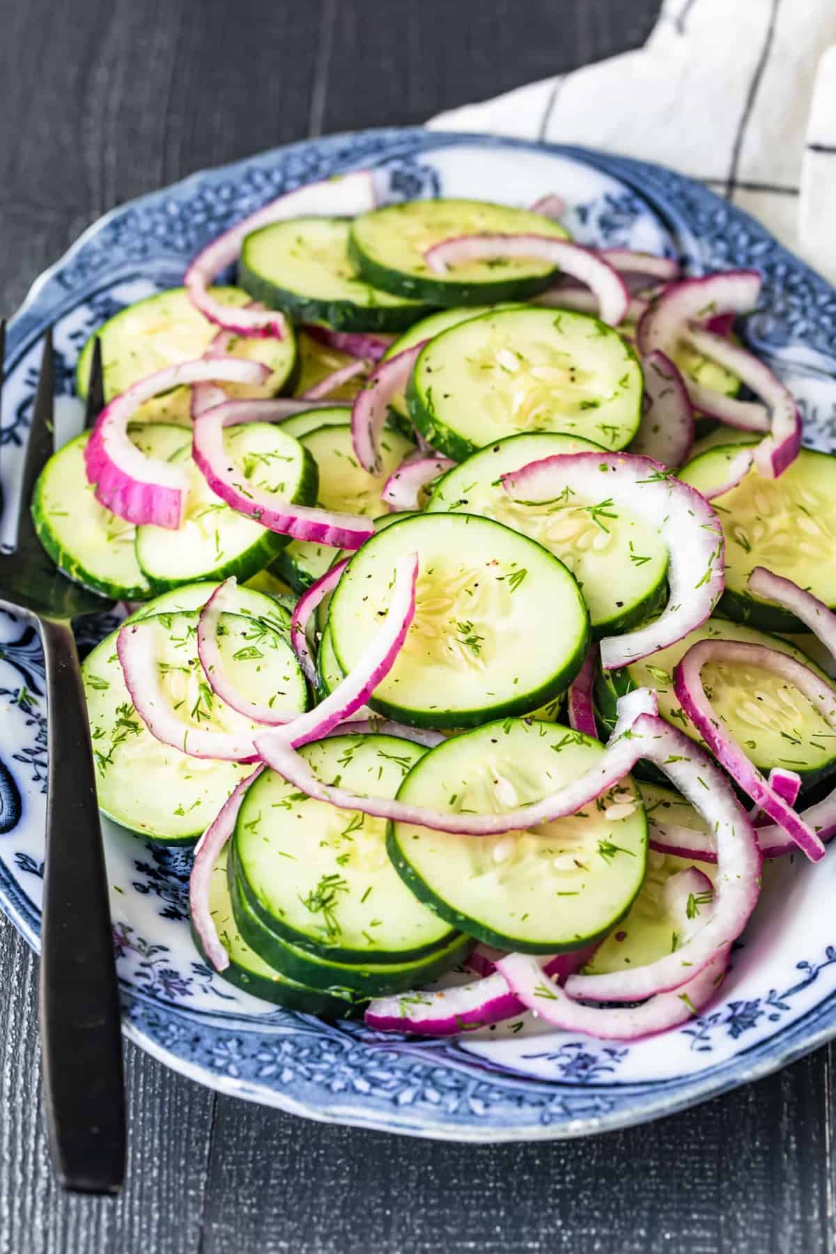 Cucumber salad with red onions on a blue and white serving plate
