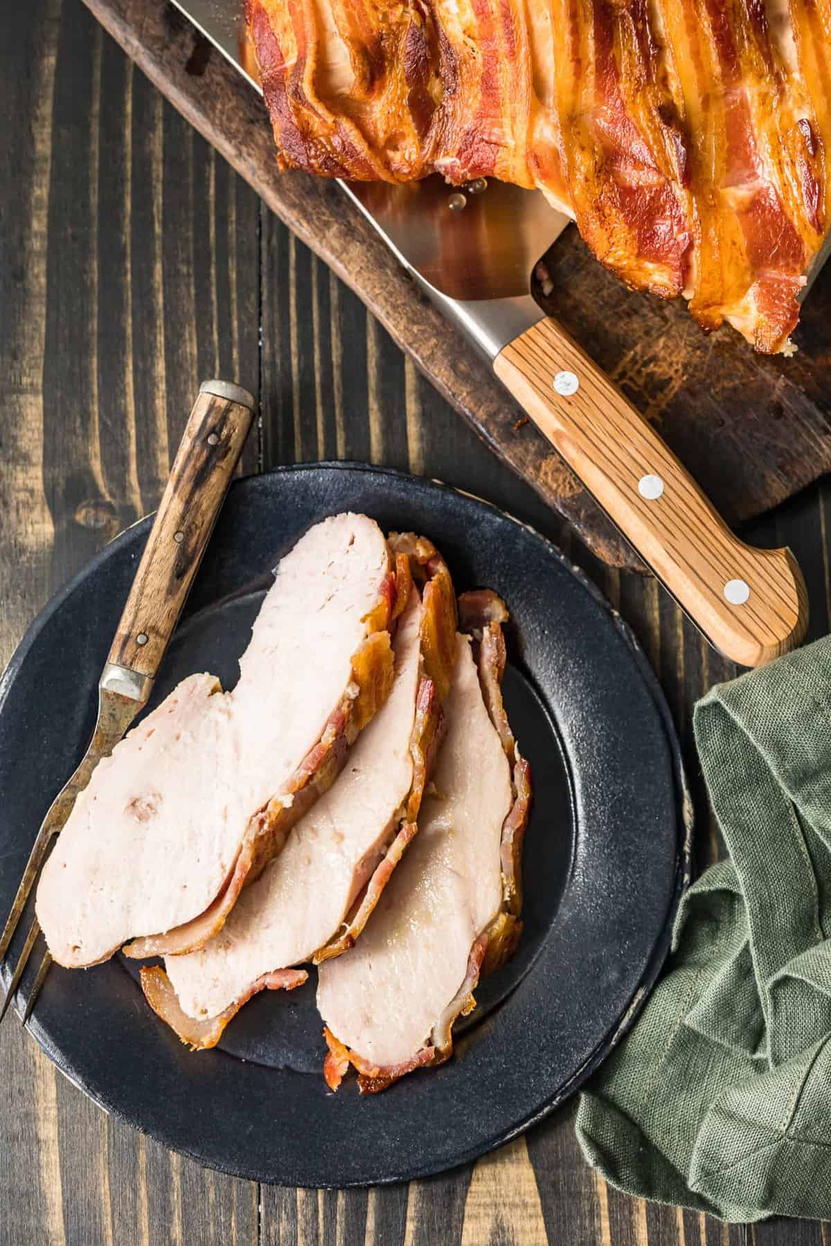 Slices of bacon wrapped turkey breast on a black plate