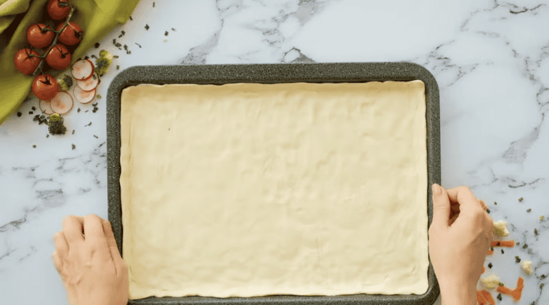 crescent roll dough spread out in a baking pan.