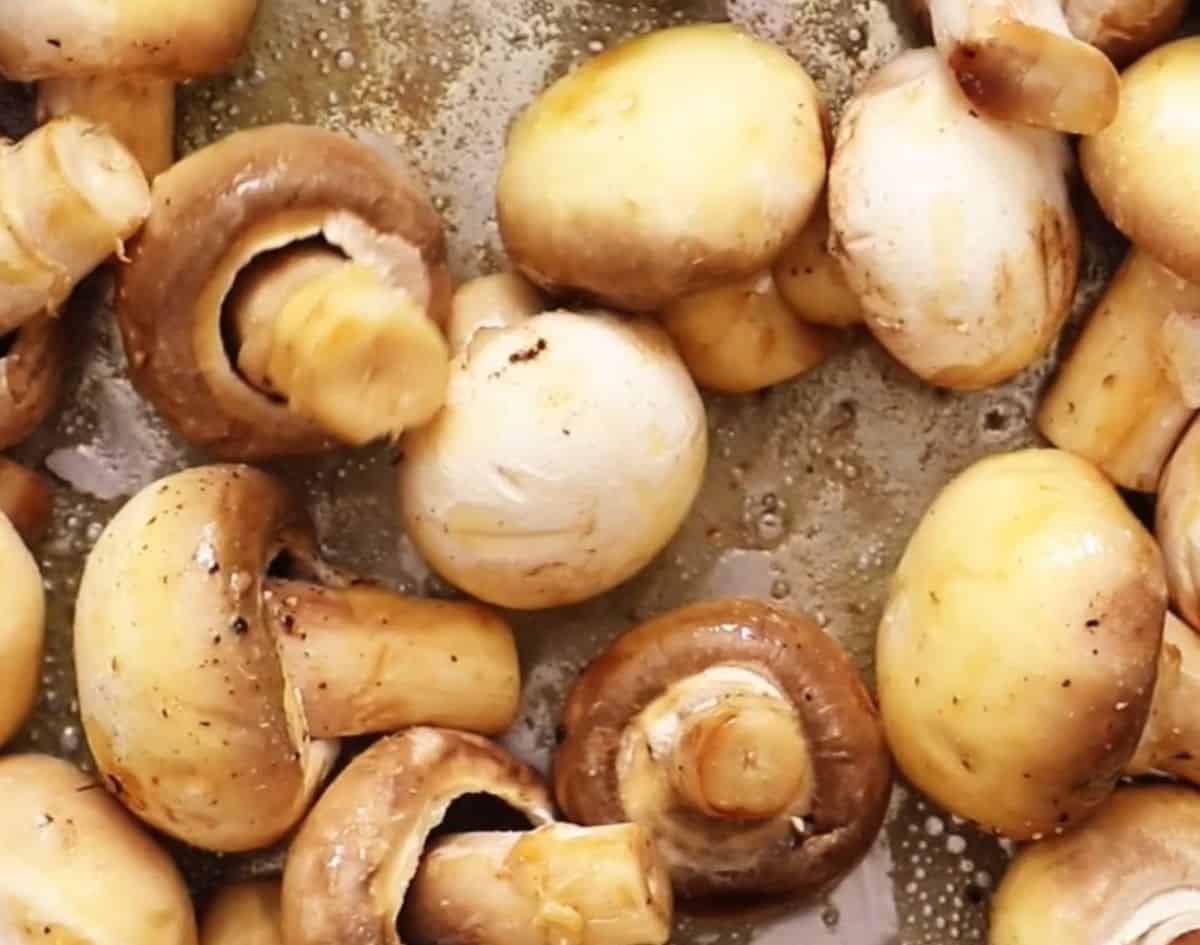 Mushrooms browning in a pan.