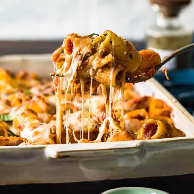 a fork is being used to take a piece of baked rigatoni out of a baking dish.