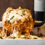 cheesy lasagna coming out of baking dish