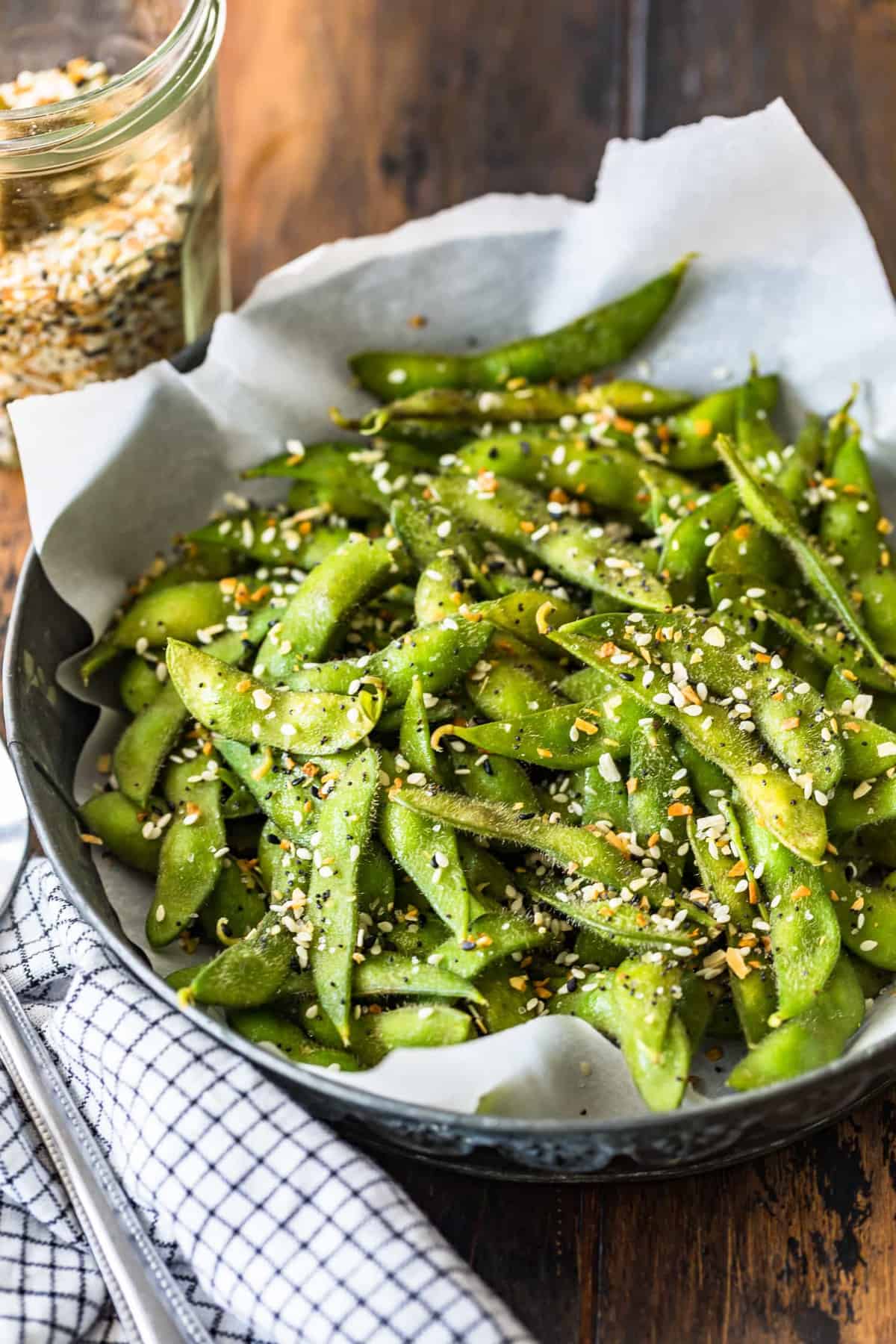 A bowl of edamame in front of a jar of everything bagel seasoning