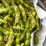Bright green edamame in a bowl seasoned with a spoon