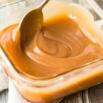 spoon stirring caramel sauce in glass container