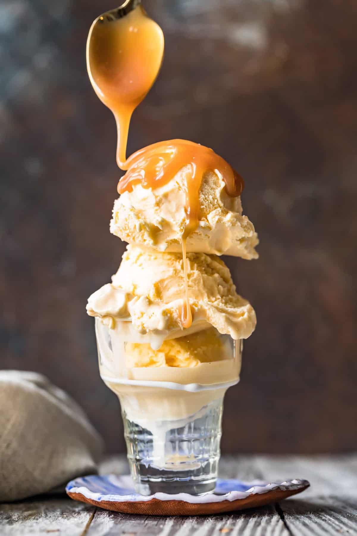 A spoon drizzling sauce on top of ice cream