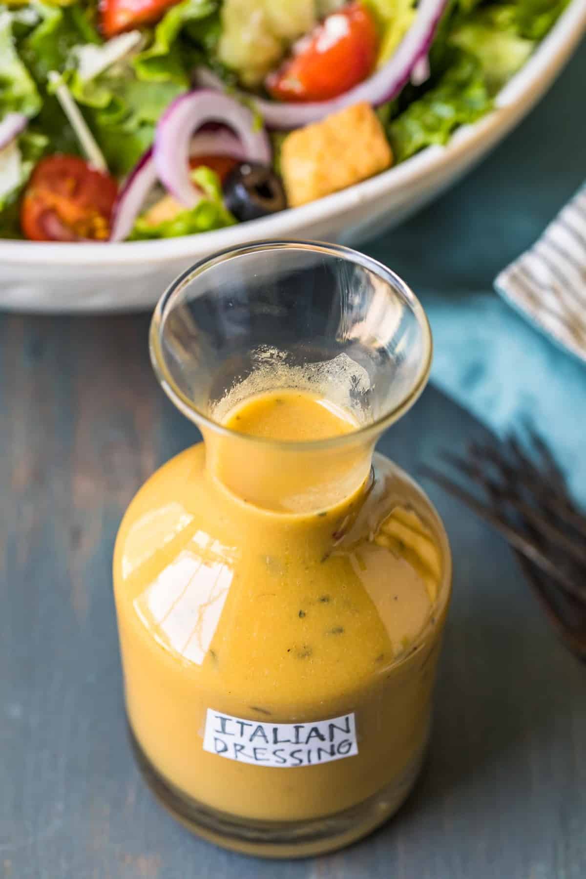 Italian dressing in a glass bottle in front of a salad