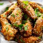 honey glazed chicken wings topped with sesame seeds and cilantro in a bowl