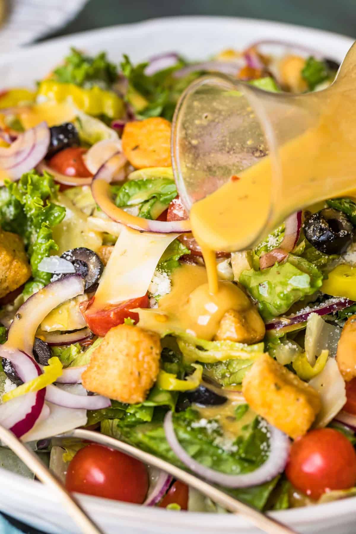 Close up of dressing being poured on the salad