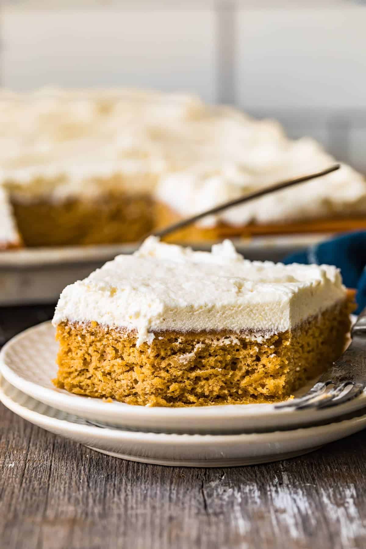 A pumpkin pie bar with icing on a white plate